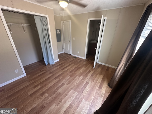 unfurnished bedroom featuring a closet, a ceiling fan, a textured ceiling, wood finished floors, and baseboards