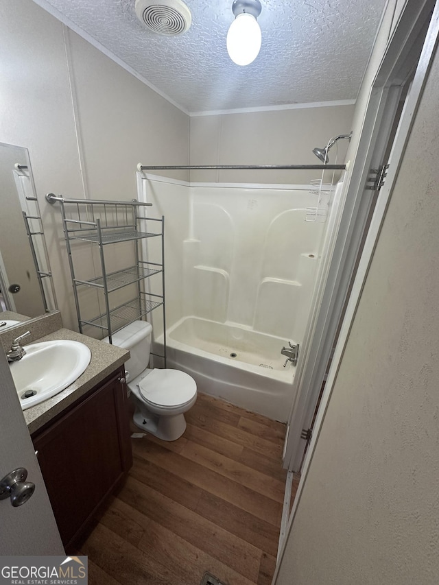 bathroom featuring a textured ceiling, toilet, wood finished floors, vanity, and visible vents