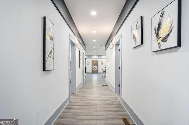 corridor with baseboards, wood finished floors, visible vents, and recessed lighting