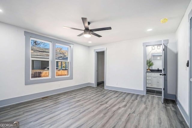 unfurnished bedroom with ensuite bath, baseboards, wood finished floors, and recessed lighting