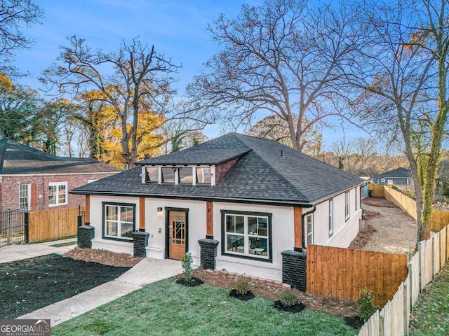 view of front facade with a fenced front yard, a front yard, and roof with shingles