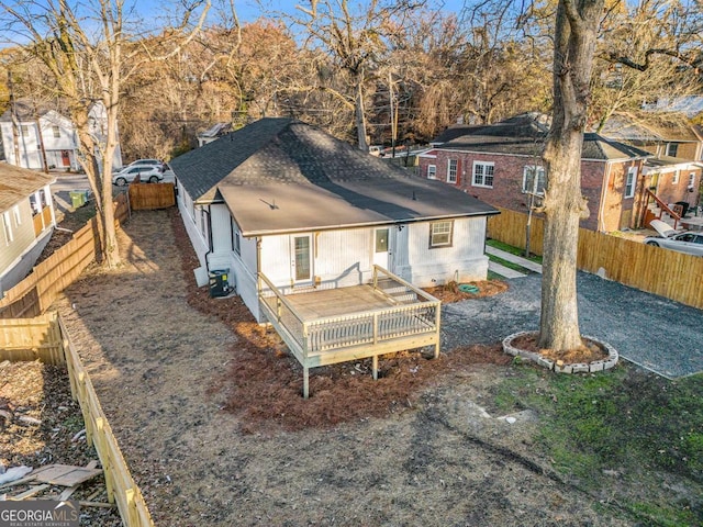 rear view of house featuring a fenced backyard and roof with shingles