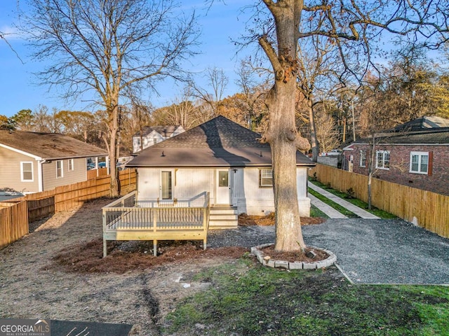 rear view of house with fence private yard, a deck, and roof with shingles