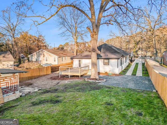 rear view of house with a fenced backyard, a lawn, and a deck