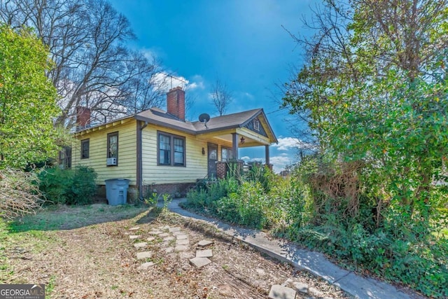 view of side of home featuring covered porch and a chimney