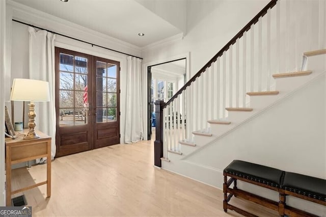 foyer entrance featuring crown molding, stairway, wood finished floors, and french doors