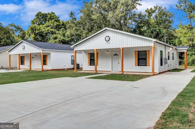 modern farmhouse style home featuring covered porch, driveway, and a front lawn