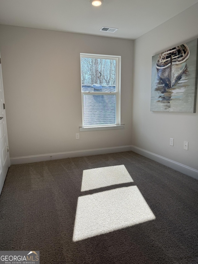 spare room with carpet flooring, visible vents, and baseboards