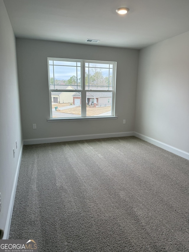 spare room featuring a healthy amount of sunlight, baseboards, visible vents, and carpet flooring