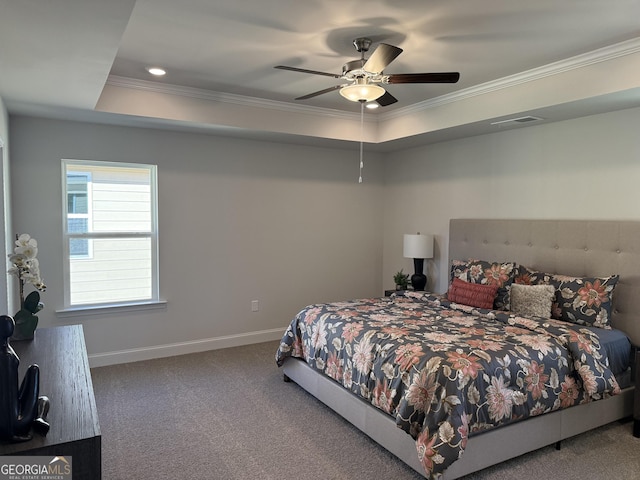 carpeted bedroom with a ceiling fan, visible vents, baseboards, ornamental molding, and a tray ceiling