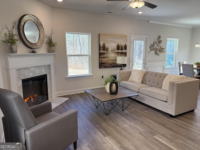 living area featuring recessed lighting, wood finished floors, visible vents, a high end fireplace, and ornamental molding