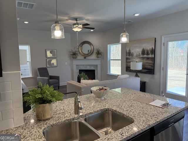 kitchen featuring a premium fireplace, a sink, visible vents, light stone countertops, and dishwasher