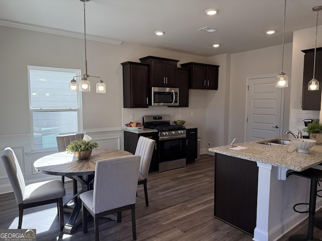 kitchen with light stone counters, dark wood-type flooring, a sink, visible vents, and appliances with stainless steel finishes