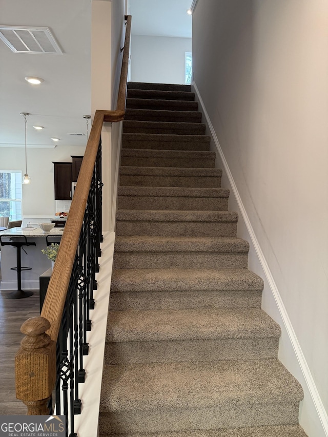 stairs with recessed lighting, a healthy amount of sunlight, visible vents, and wood finished floors