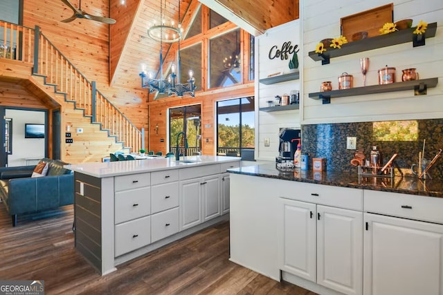 kitchen with wooden walls, white cabinetry, open shelves, and dark wood-style flooring