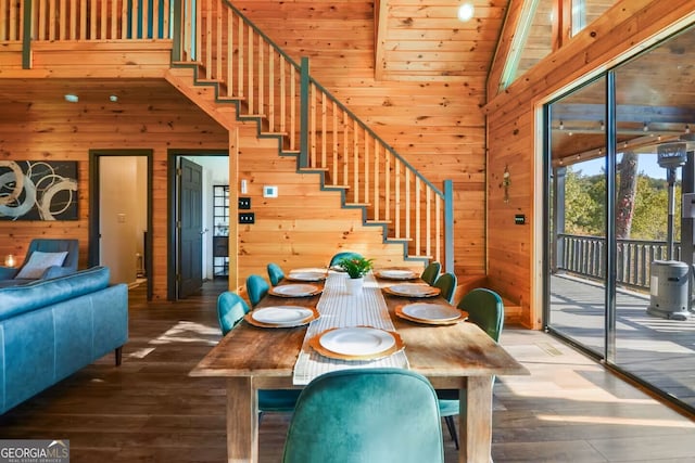 dining space with wood finished floors, wooden walls, and stairs