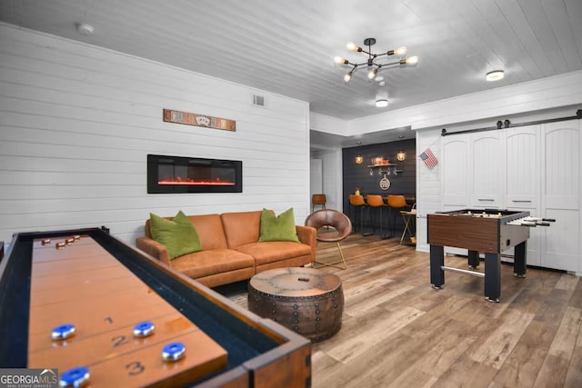 playroom featuring visible vents, a barn door, a glass covered fireplace, wood finished floors, and wooden ceiling