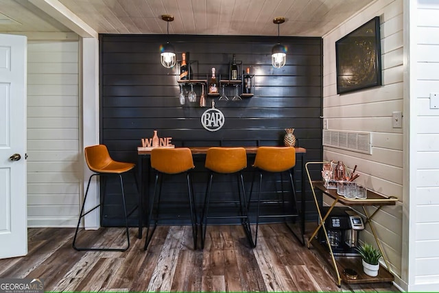 bar featuring wooden ceiling, a bar, and wood finished floors