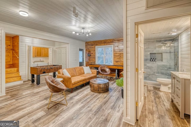 living area featuring light wood-type flooring, wood walls, wood ceiling, and stairway