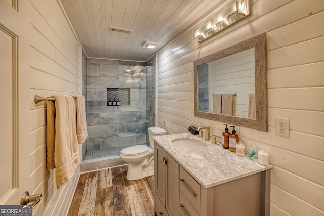 full bath with visible vents, toilet, a tile shower, wood finished floors, and wooden ceiling