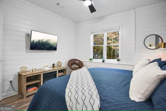 bedroom featuring ceiling fan, wood finished floors, visible vents, and crown molding