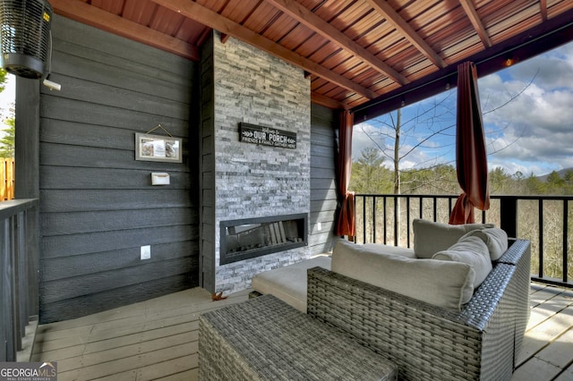 exterior space featuring vaulted ceiling with beams, plenty of natural light, and an outdoor stone fireplace