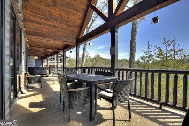 deck featuring outdoor dining area and a hot tub