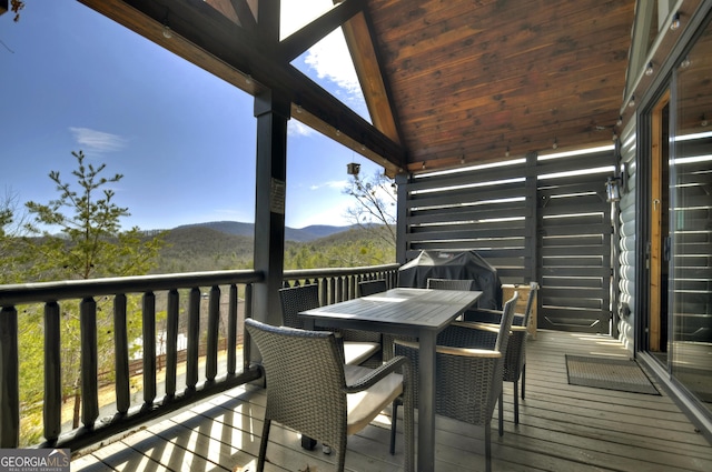 wooden terrace with outdoor dining area and a mountain view