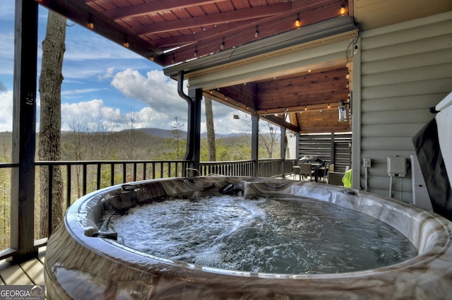 wooden deck featuring a mountain view and a hot tub