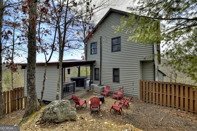 rear view of house featuring a fire pit and fence