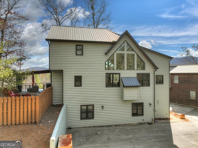 rear view of house with fence and metal roof