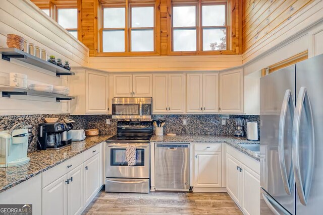 kitchen with stainless steel appliances, a sink, decorative backsplash, and open shelves