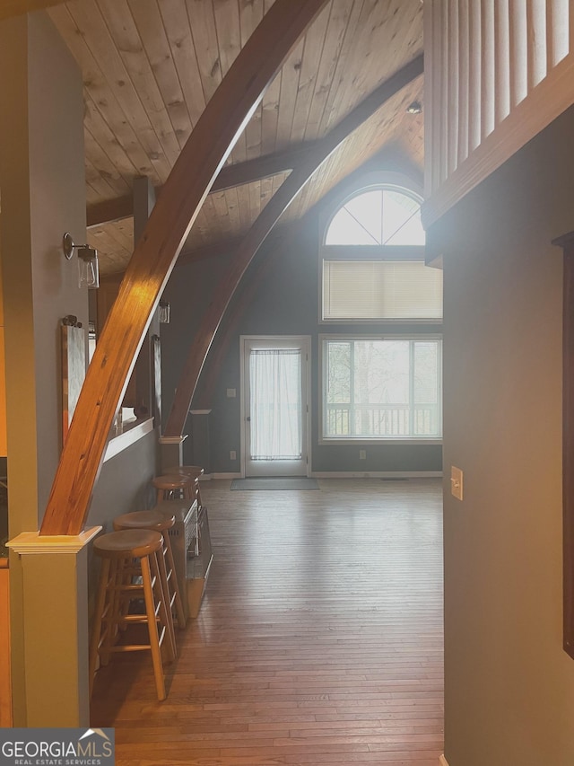 unfurnished living room with lofted ceiling with beams, wood finished floors, wood ceiling, baseboards, and stairs