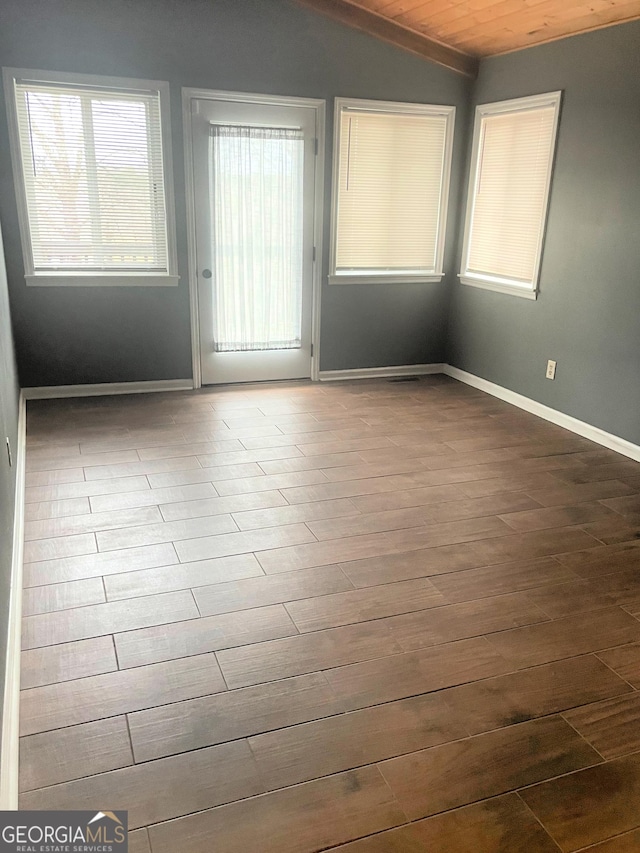 spare room with lofted ceiling, baseboards, and dark wood-style flooring