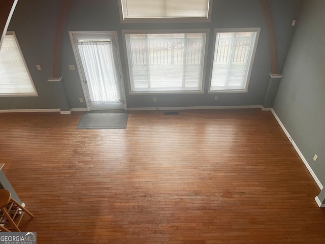 unfurnished living room featuring hardwood / wood-style flooring and baseboards