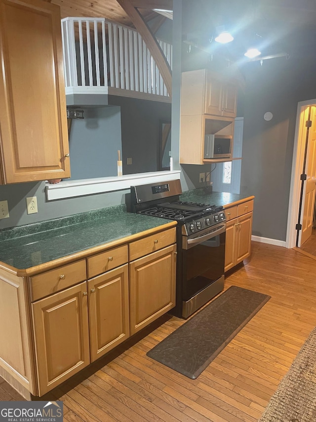 kitchen featuring stainless steel range with gas cooktop, baseboards, and light wood finished floors