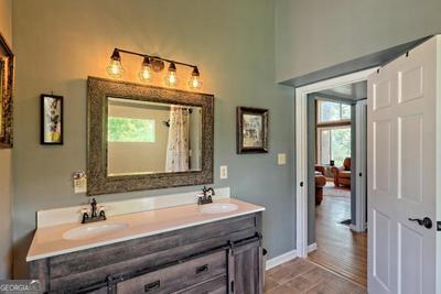 bathroom featuring a shower with shower curtain, a sink, baseboards, and double vanity