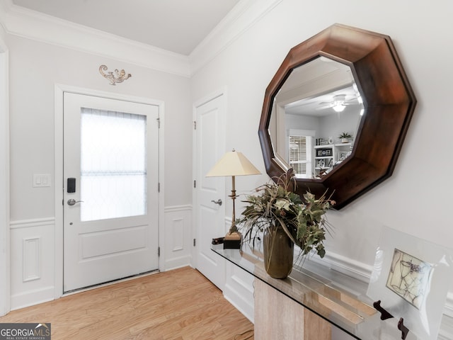 entryway with light wood-type flooring, a wainscoted wall, plenty of natural light, and crown molding