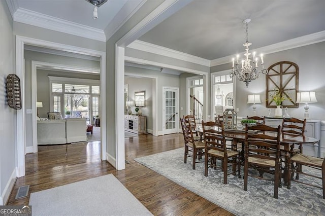 dining area with a notable chandelier, crown molding, visible vents, and wood finished floors