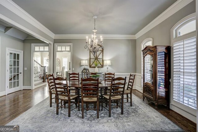 dining space with plenty of natural light, crown molding, a chandelier, and wood finished floors