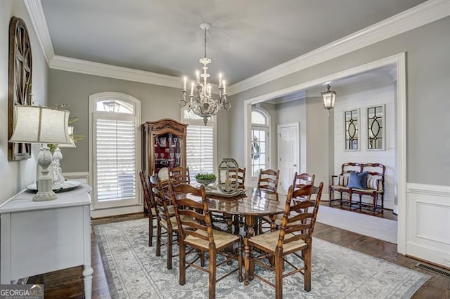 dining space with visible vents, crown molding, a notable chandelier, and wood finished floors