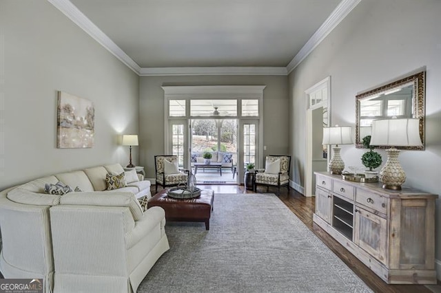 living room featuring dark wood-type flooring, crown molding, and baseboards