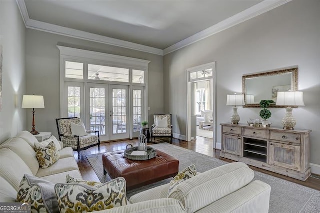 living room with french doors, crown molding, baseboards, and wood finished floors