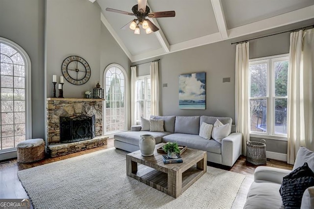 living room with beam ceiling, a fireplace, a ceiling fan, wood finished floors, and high vaulted ceiling