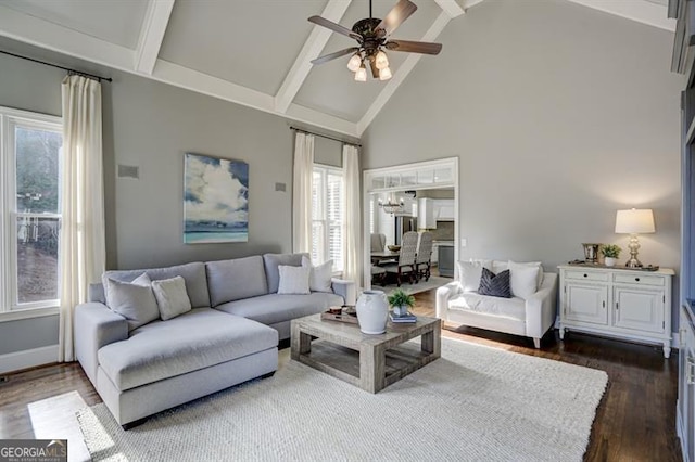 living room featuring high vaulted ceiling, ceiling fan with notable chandelier, baseboards, beam ceiling, and dark wood-style floors