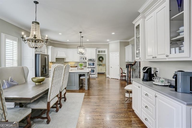 dining area with a chandelier, dark wood-type flooring, crown molding, and recessed lighting