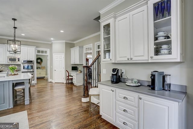 kitchen with white cabinetry, appliances with stainless steel finishes, a breakfast bar, and crown molding