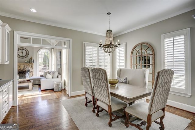 dining space with a notable chandelier, crown molding, baseboards, and wood finished floors