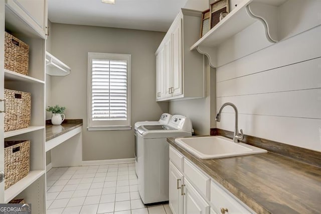 laundry room with cabinet space, light tile patterned flooring, a sink, independent washer and dryer, and baseboards