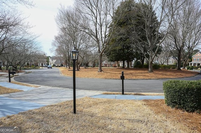 view of road featuring sidewalks, a residential view, and street lights